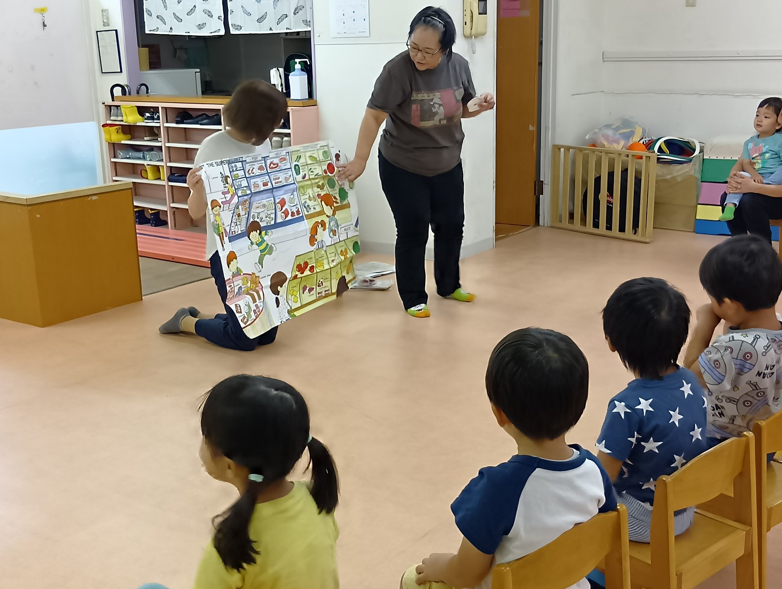 英語指導で講師の絵本を見る子どもたち