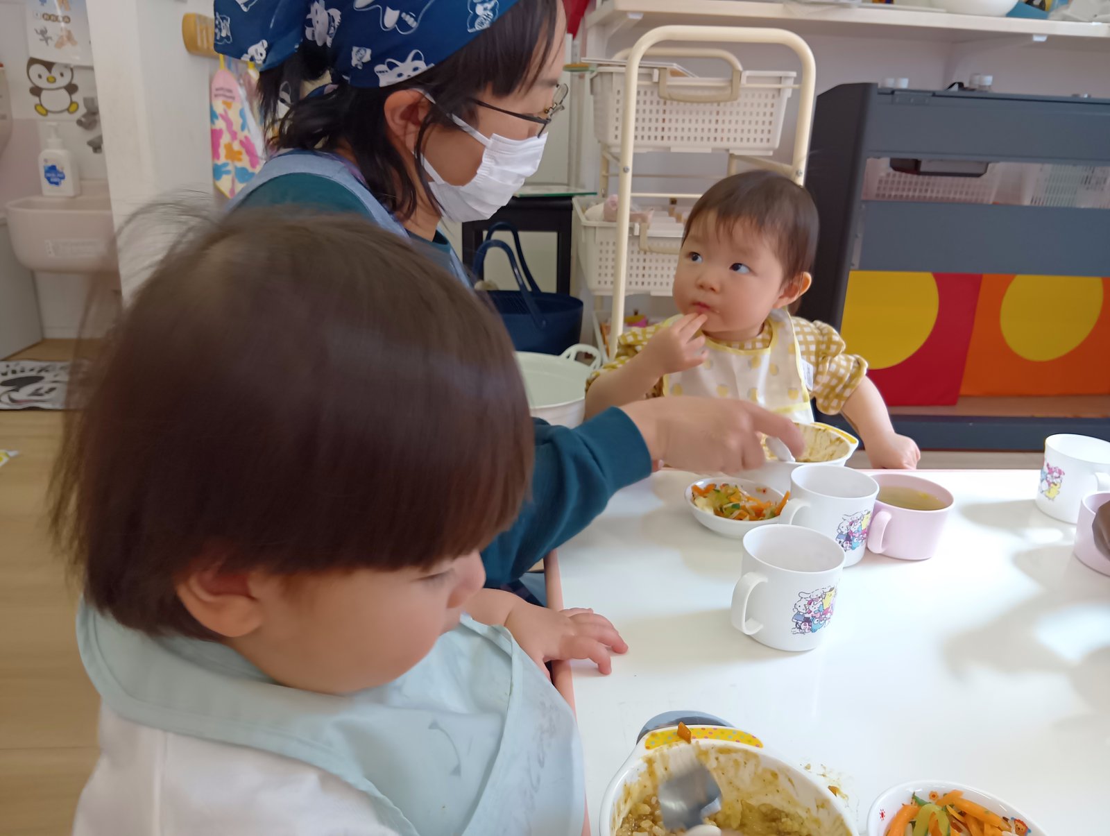 保育士に見守られて給食を食べる子どもたち