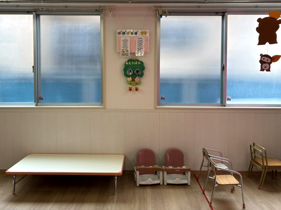 窓から光が入る保育室。テーブルと子ども用の椅子が並ぶ