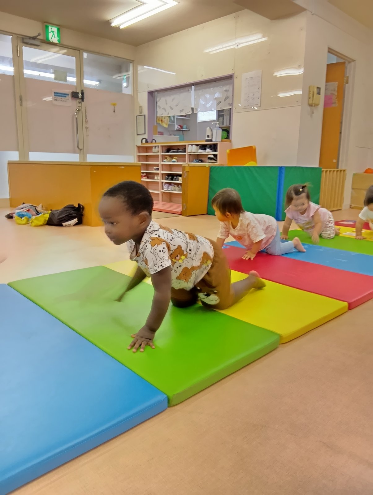 マットの上をはいはいで進む子どもたち