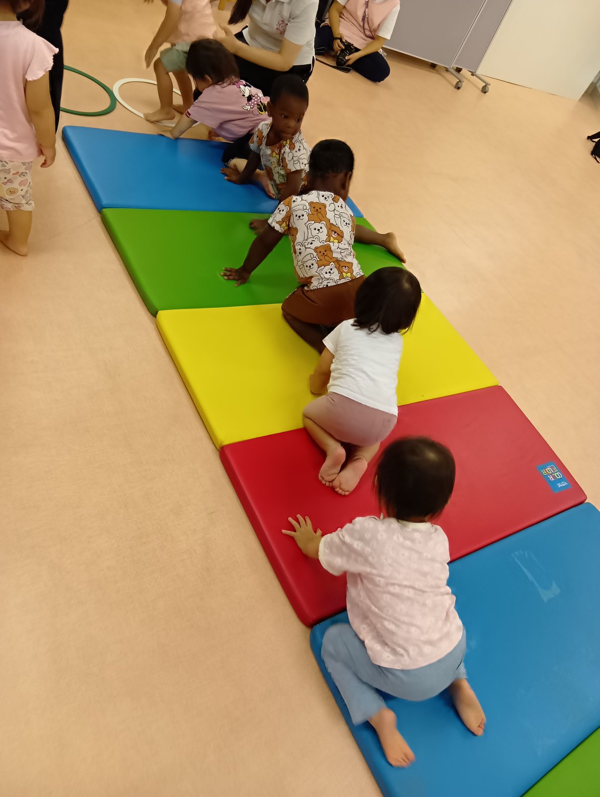 プチ体操でマットの上をはいはいで進む子どもたち